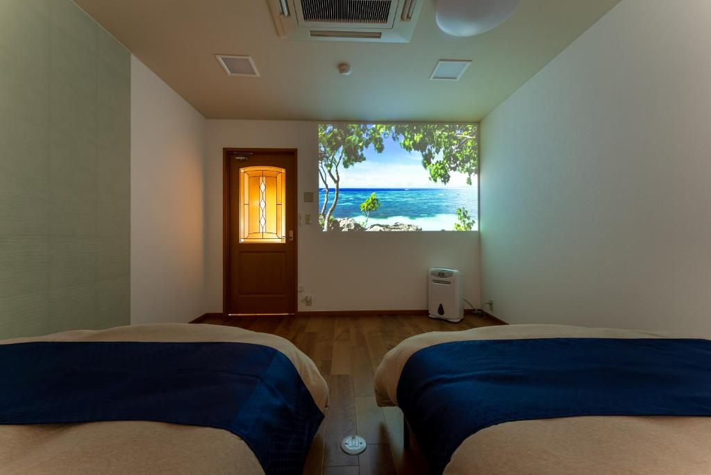 a room with two beds and a window with the ocean at Noёl HAKONE GENSEN in Hakone