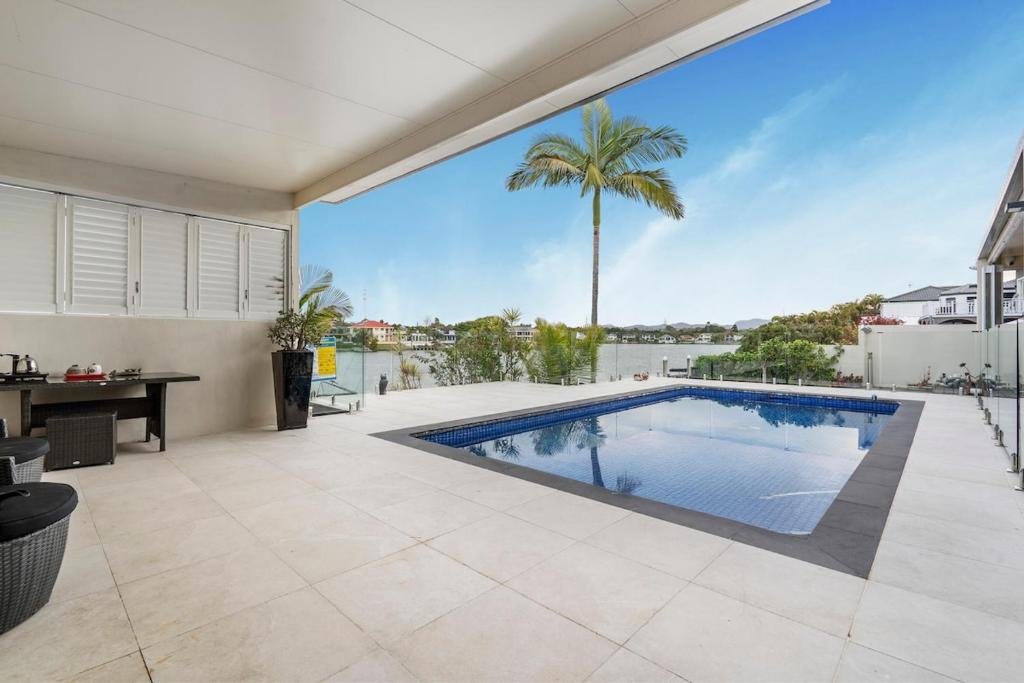 ゴールドコーストにあるSerene 5BR Waterfront Escape - Prestigeのヤシの木があるヴィラ内のスイミングプール