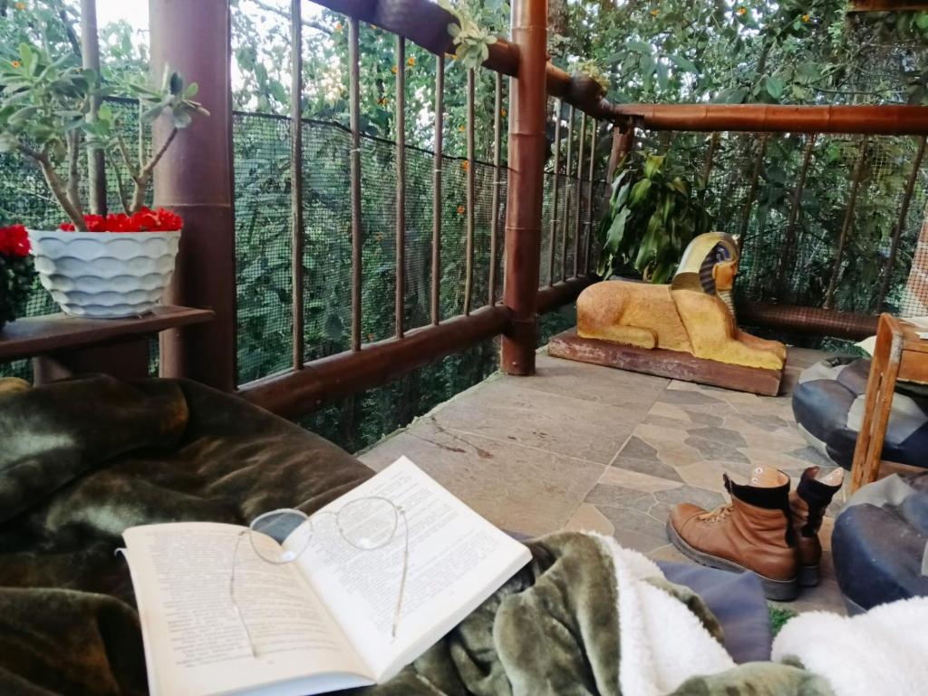 a porch with a couch with a book on it at Boresta House -Santa Elena con vista al Bosque y terraza privada in Medellín