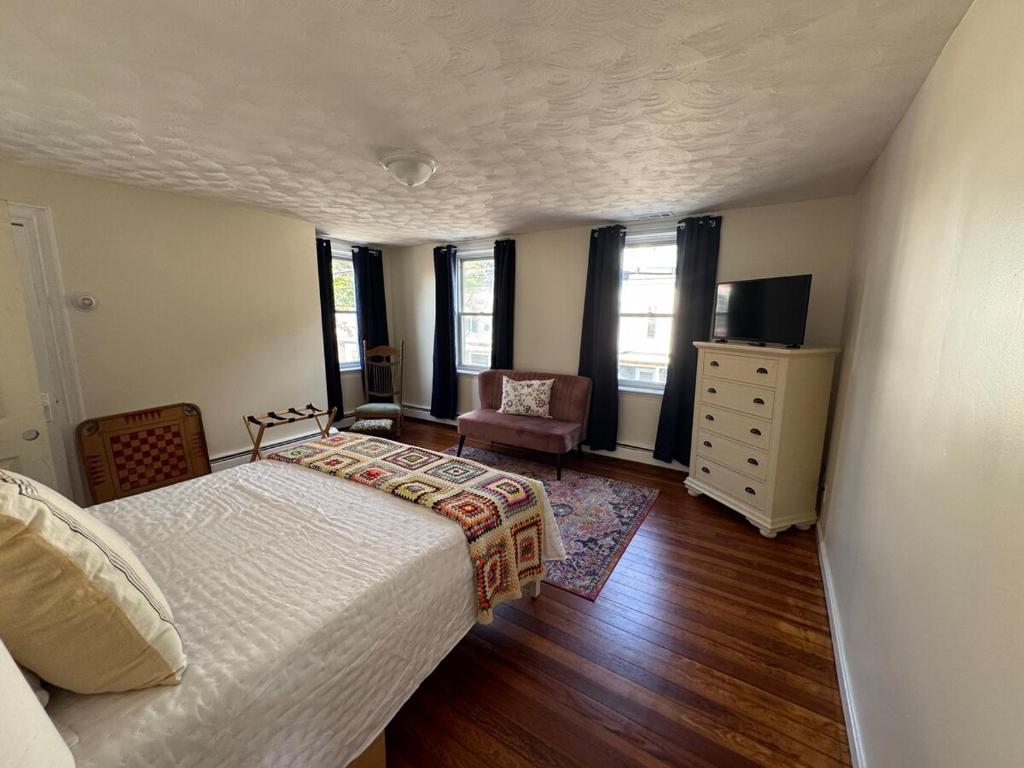 a bedroom with a bed and a chair and a dresser at Seaside Stay in Historic Warren in Warren