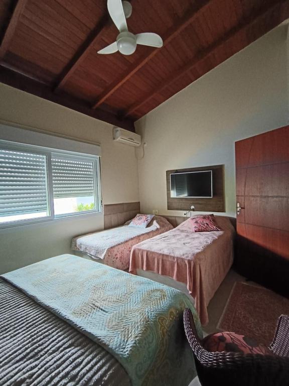 a bedroom with two beds and a ceiling fan at Pousada Familiar Morada Lua Nova in Florianópolis