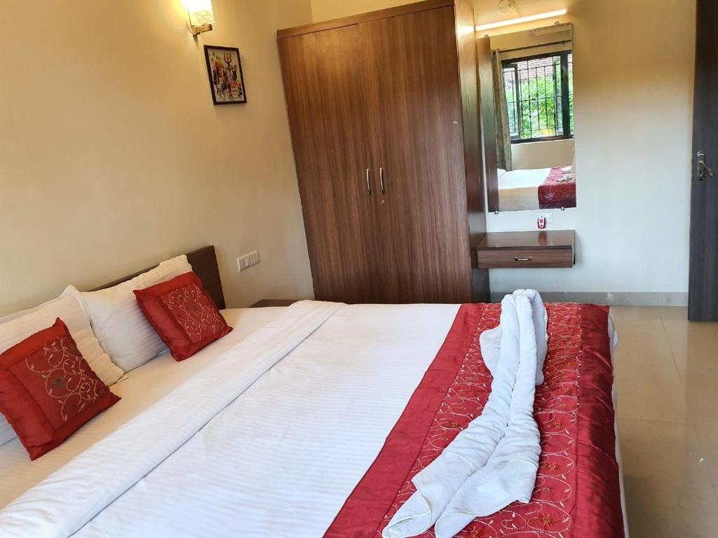 a bedroom with a large bed with red and white sheets at Candolim apartment in Candolim