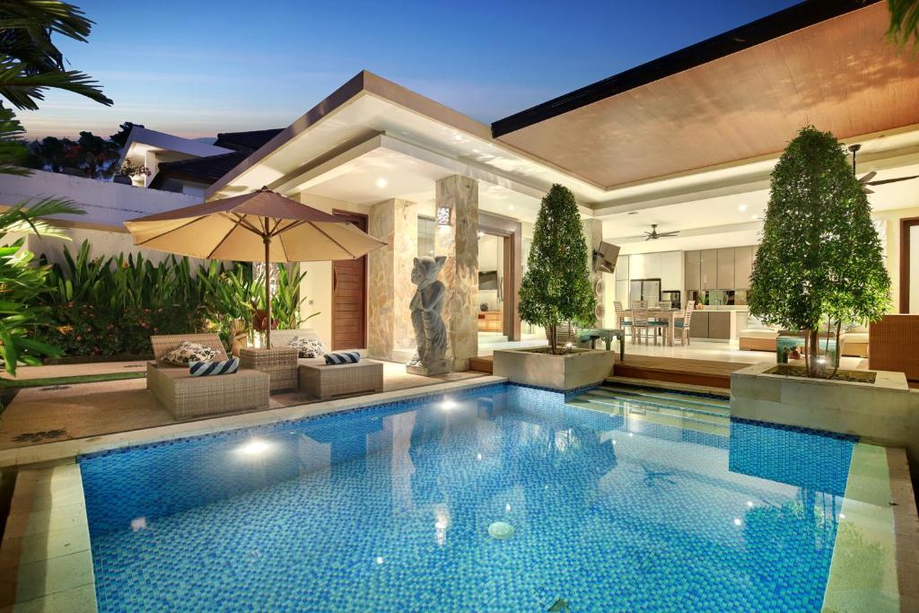 a swimming pool with an umbrella in a house at Villa J Deluxe in Canggu
