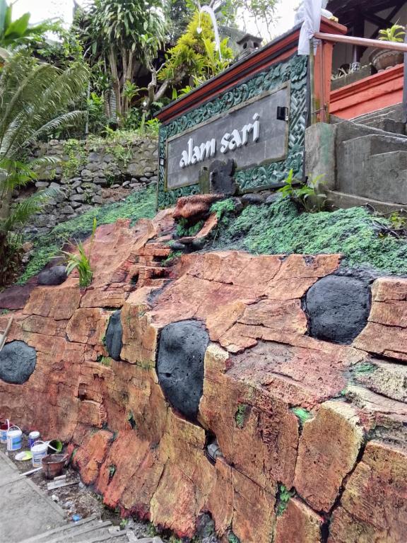 a sign on top of a rock wall at The Chapel Alam Sari Ubud in Ubud