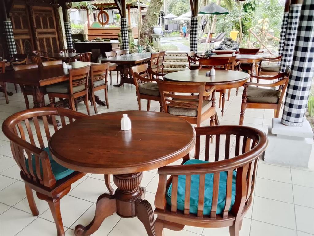 une salle à manger avec des tables et des chaises en bois dans l'établissement The Chapel Alam Sari Ubud, à Ubud
