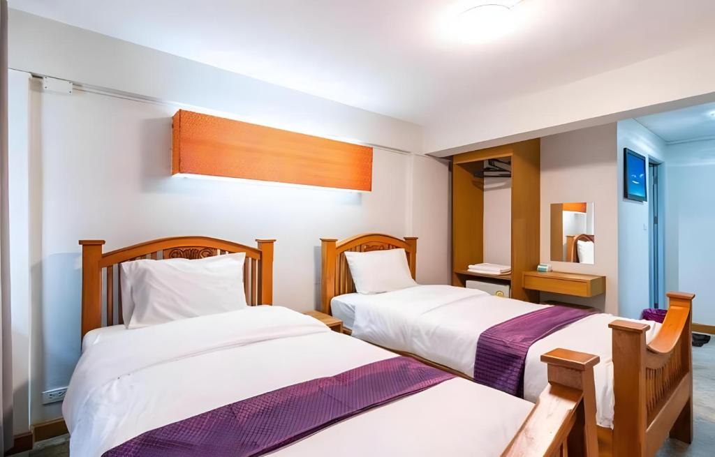 ein Schlafzimmer mit zwei Betten und einem Spiegel in der Unterkunft XX GO INN Khaosan Chakraphong in Bang Bua Thong Railway Station