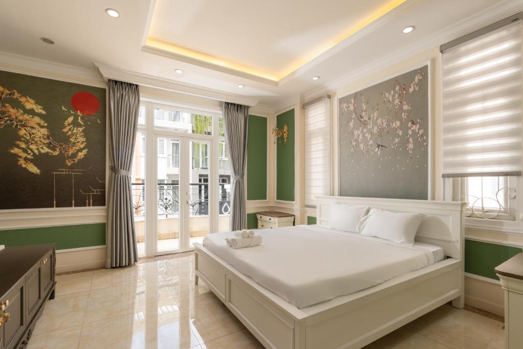 a bedroom with a large white bed and windows at Villa INDOCHINA 7 bed room in Ho Chi Minh City