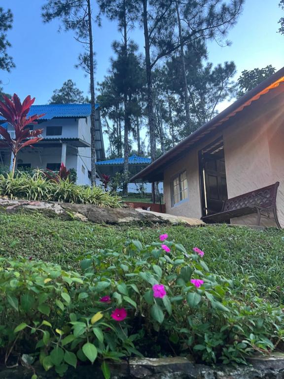 una casa con flores rosas en un patio en La Cabañita, en Los Altos de Cerro Azul