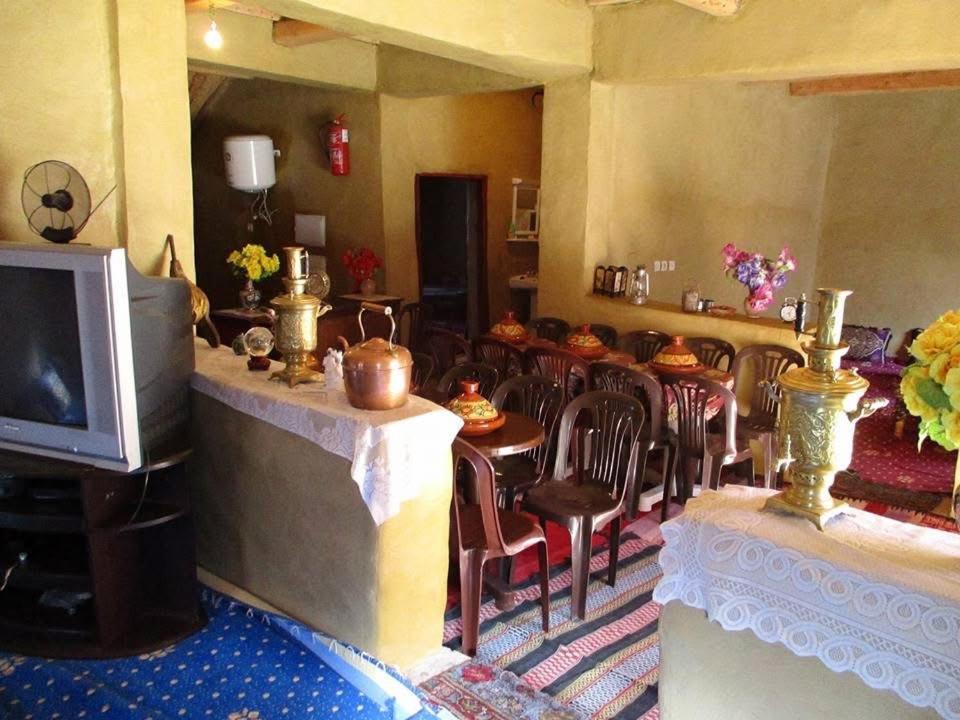 Una sala de estar con una mesa y sillas y un televisor. en دار اوليم, en Annoums