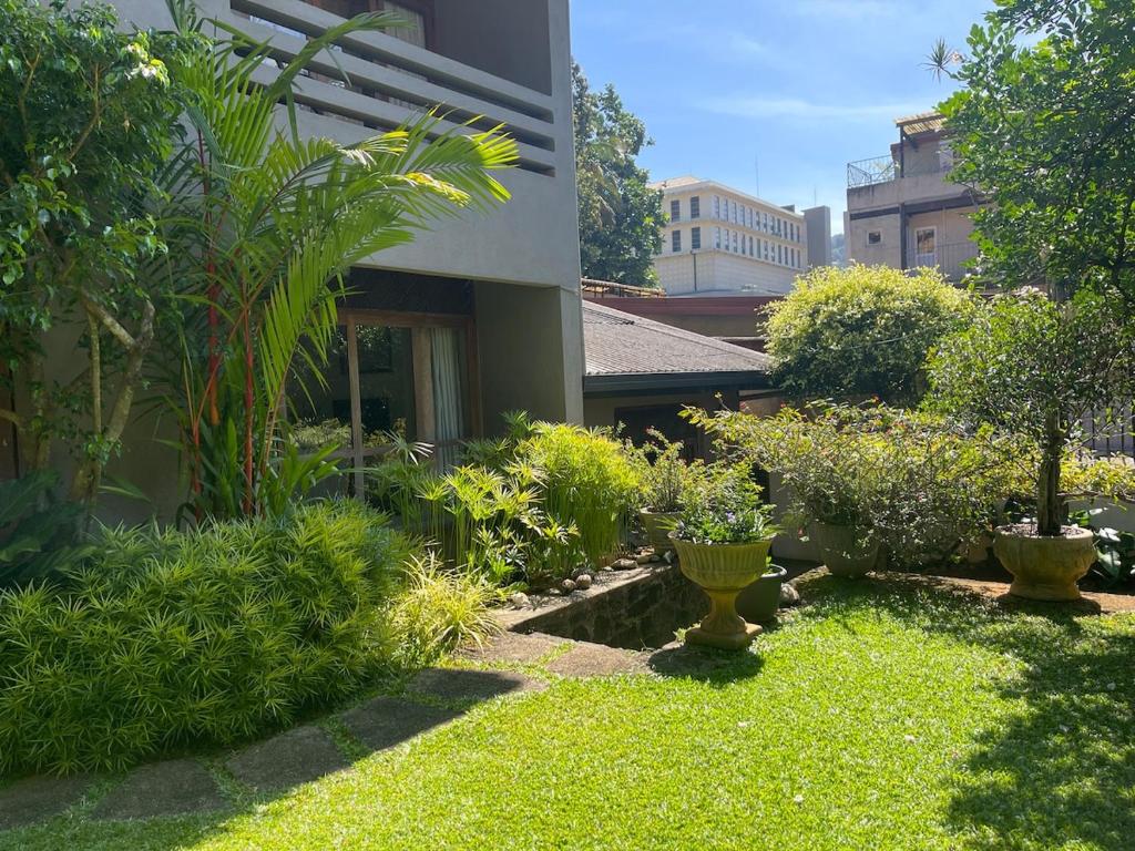 einem Garten mit grünen Pflanzen und einem Gebäude in der Unterkunft Kandy - City Hideout Villa in Kandy