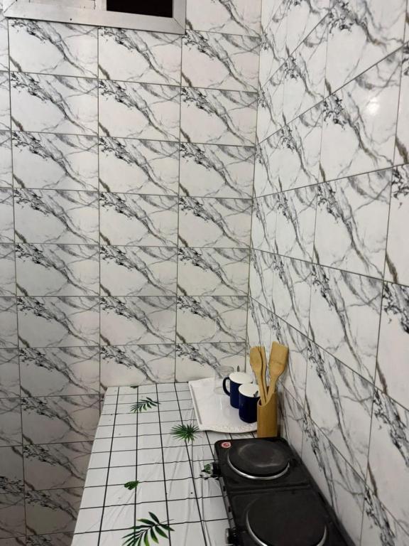 a bathroom with a black toilet and white tiles at Mini studio in Dakar