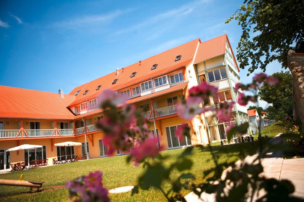 JUFA Hotel Nördlingen في نوردلينغن: مبنى برتقالي مع زهور وردية أمامه
