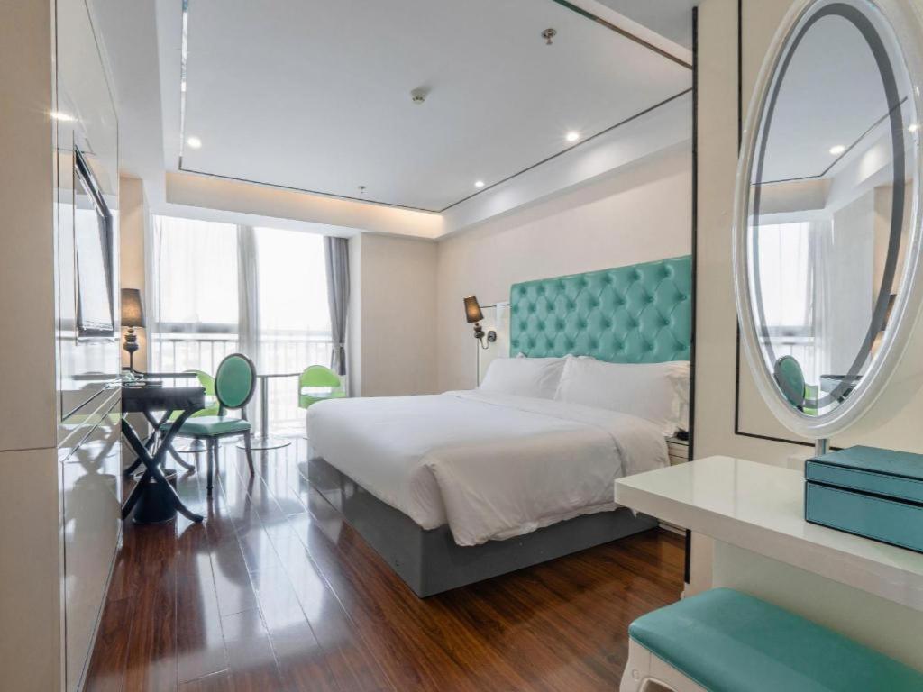 1 dormitorio con 1 cama grande y espejo redondo en Xana Lite Anqing Yuexi Swan Squre Branch, en Yuexi