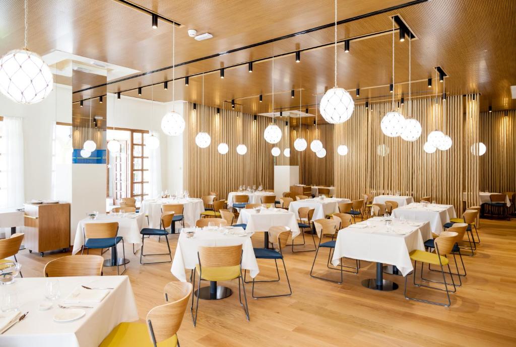 a restaurant with white tables and chairs and chandeliers at Iberostar Selection Andalucia Playa in Chiclana de la Frontera