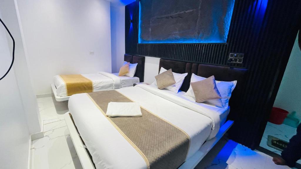 two beds in a small room with blue lights at GM Residency in Varanasi