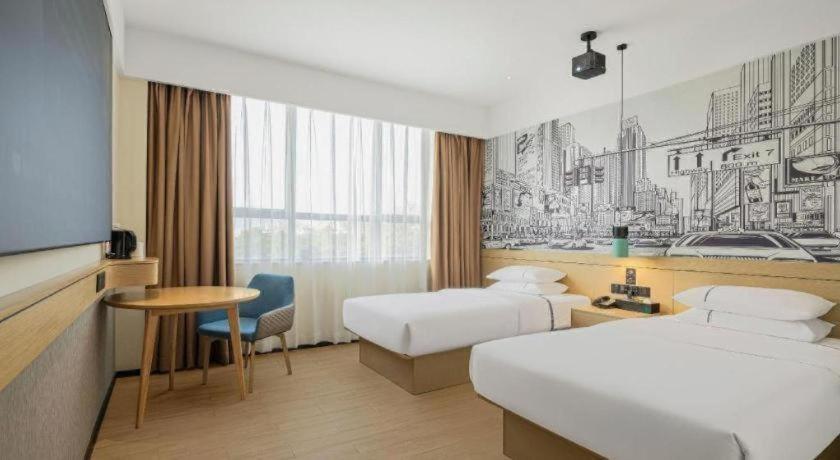 a hotel room with two beds and a tv at City Comfort Inn Zhanjiang Middle Haibin Avenue Wanda Plaza in Zhanjiang
