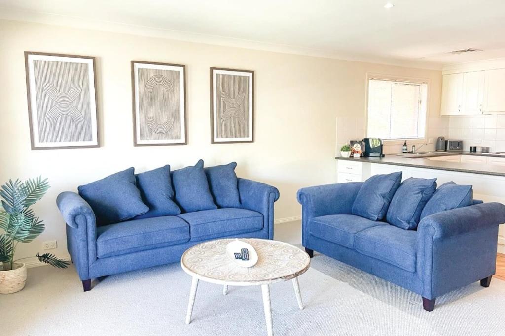 a living room with two blue couches and a table at Glens Parkview Apartments in Wagga Wagga