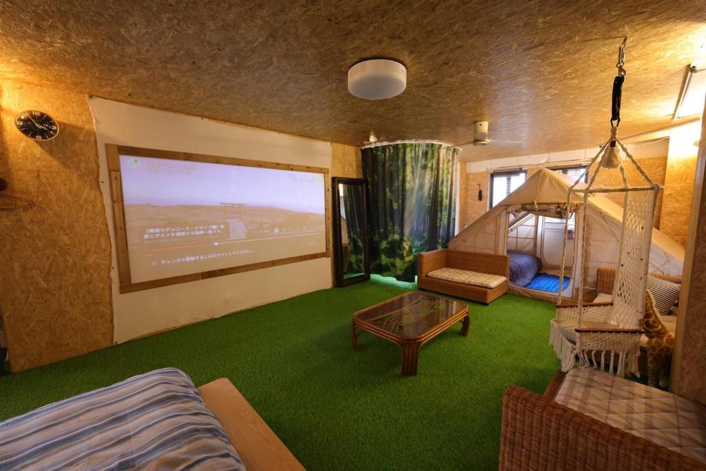 a living room with a couch and a large screen at HB01 テントと芝生が広がるお部屋 小田原港3分 8名可 箱根板橋駅徒歩8分 早川駅徒歩7分 Tent and lawn room Odawara Port 3 minutes 8 people Hakone Itabashi Station 8 minutes on foot Hayakawa Station 7 minutes on foot in Odawara
