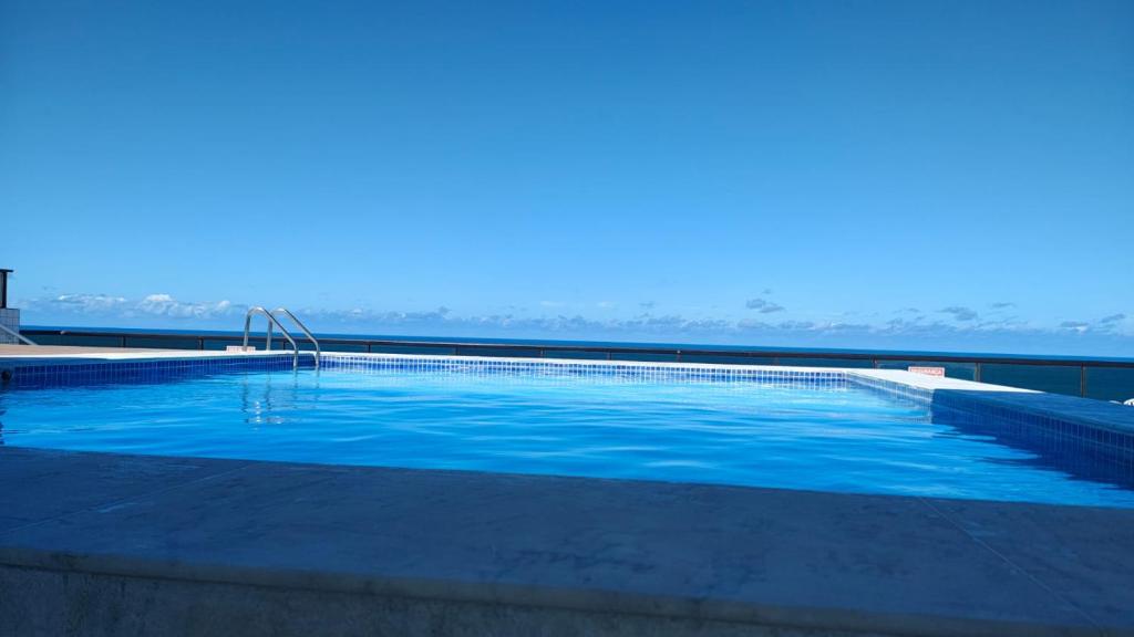 a large swimming pool with blue water in the foreground at Flet do condominio flet 4 rodas in Olinda