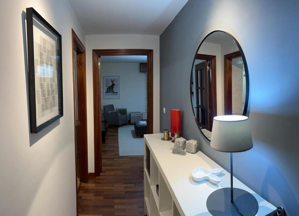 een badkamer met een spiegel en een tafel met een lamp bij apartamento completo in El Burgo