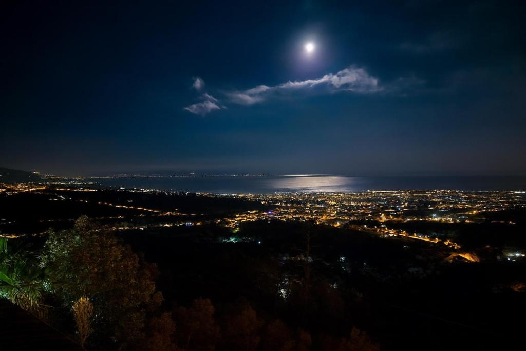 a view of a city at night with the moon at Casacircuetnea in Piedimonte Etneo