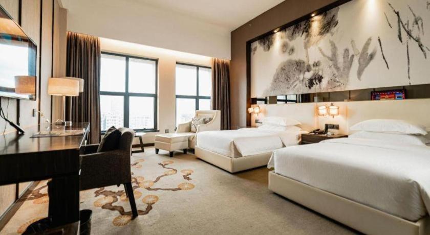 een slaapkamer met 2 bedden, een bureau en een piano bij Zhuhai HongJingWan Hotel in Hongwan