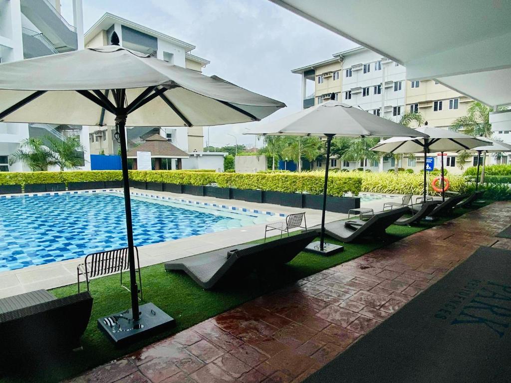 ein Pool mit Sonnenschirmen neben einem Gebäude in der Unterkunft SMDC Park Residences Condo Unit 417 near SM City Sta Rosa in Ibaba