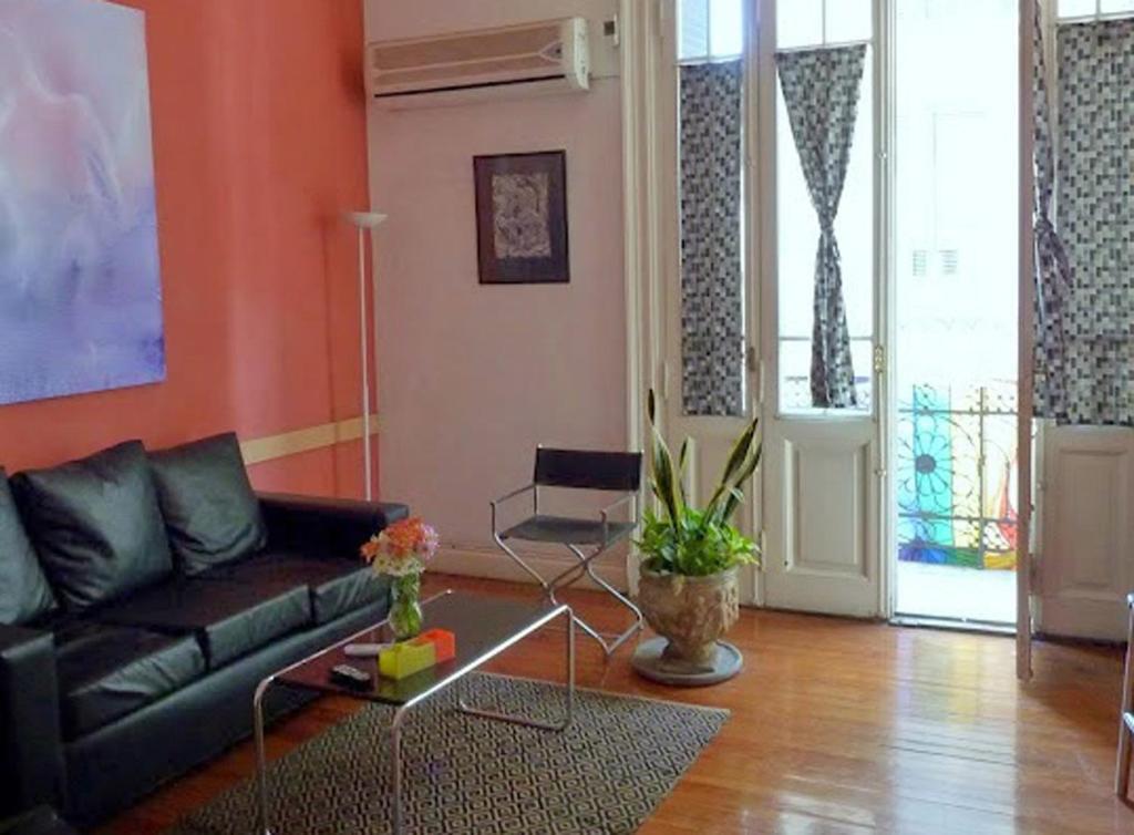 ein Wohnzimmer mit einem schwarzen Sofa und orangefarbenen Wänden in der Unterkunft LGY G A Y Bed & Breakfast ONLY MEN in Buenos Aires