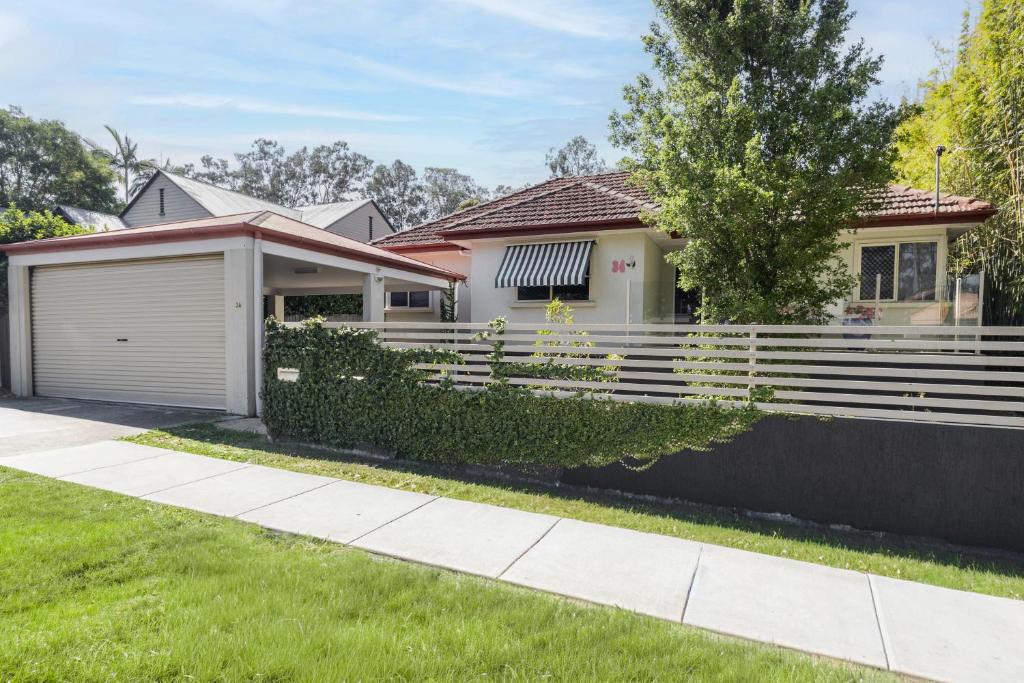 una casa con una recinzione e un cortile di Bird and Leaf Cottage a Brisbane