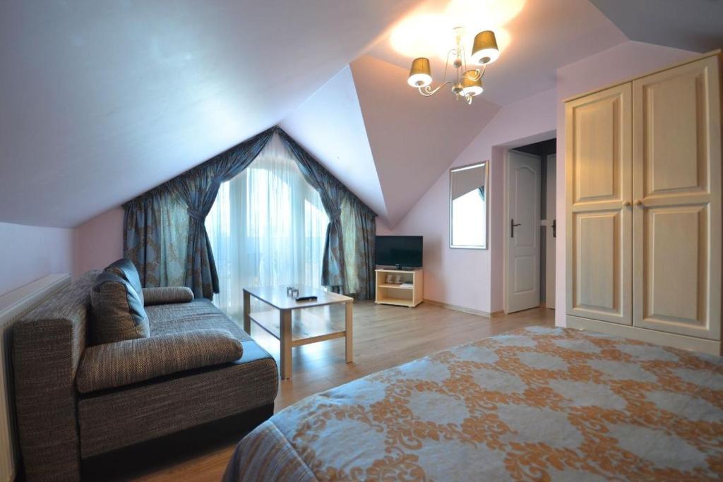 ein Schlafzimmer mit einem Bett, einem Sofa und einem TV in der Unterkunft Willa Słowiańska in Misdroy