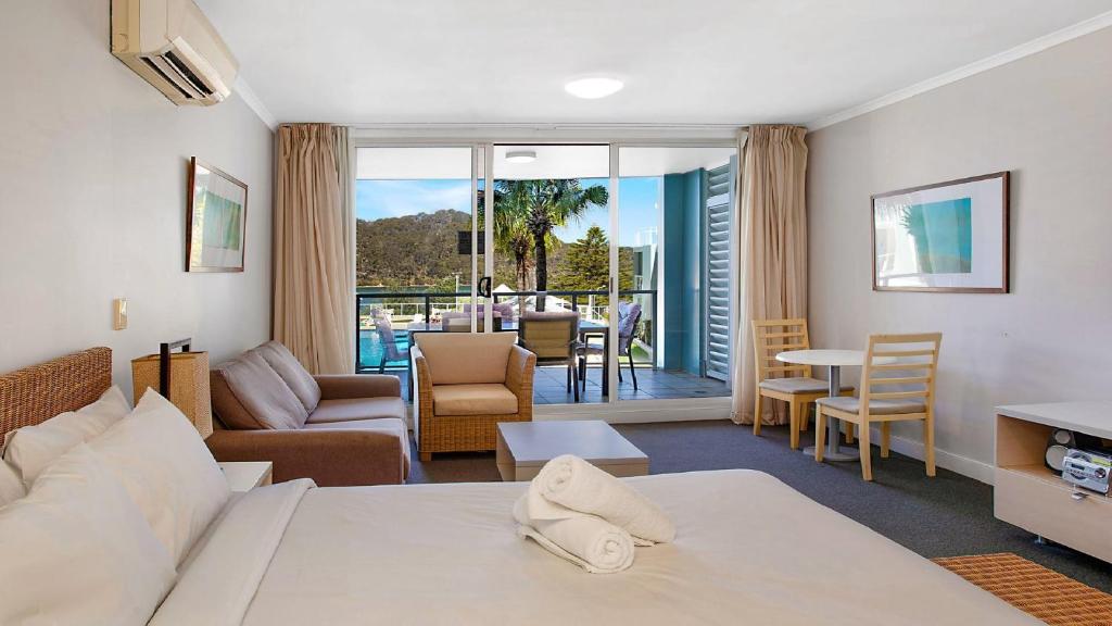 a hotel room with a bed and a living room at Vista Mare - Beachside Studio With Stunning Views in Ettalong Beach