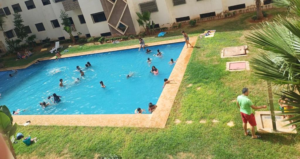 a group of people swimming in a swimming pool at Très beau appartement avec piscine in Casablanca