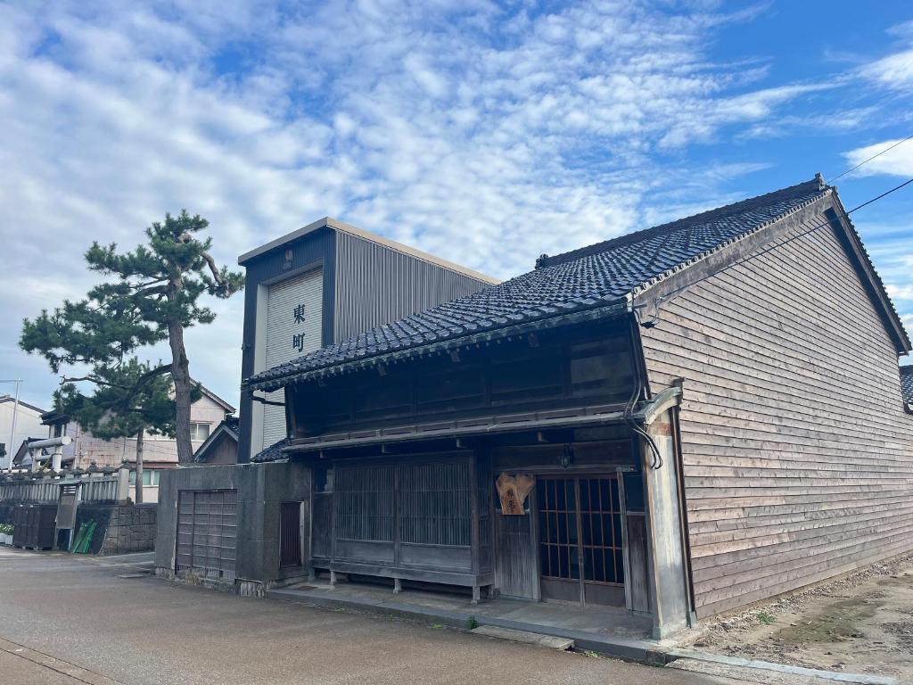 Um cachorro está com a cabeça para fora de um prédio. em 古民家宿 禅楽 em Shimminato