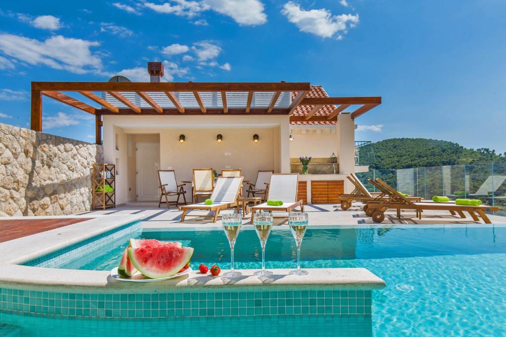 eine Villa mit einem Pool mit einer Scheibe Wassermelone auf dem Tisch in der Unterkunft Villa Boban in Dubrovnik