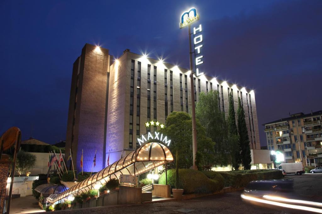 a hotel building with a sign on it at night at Hotel Maxim in Verona