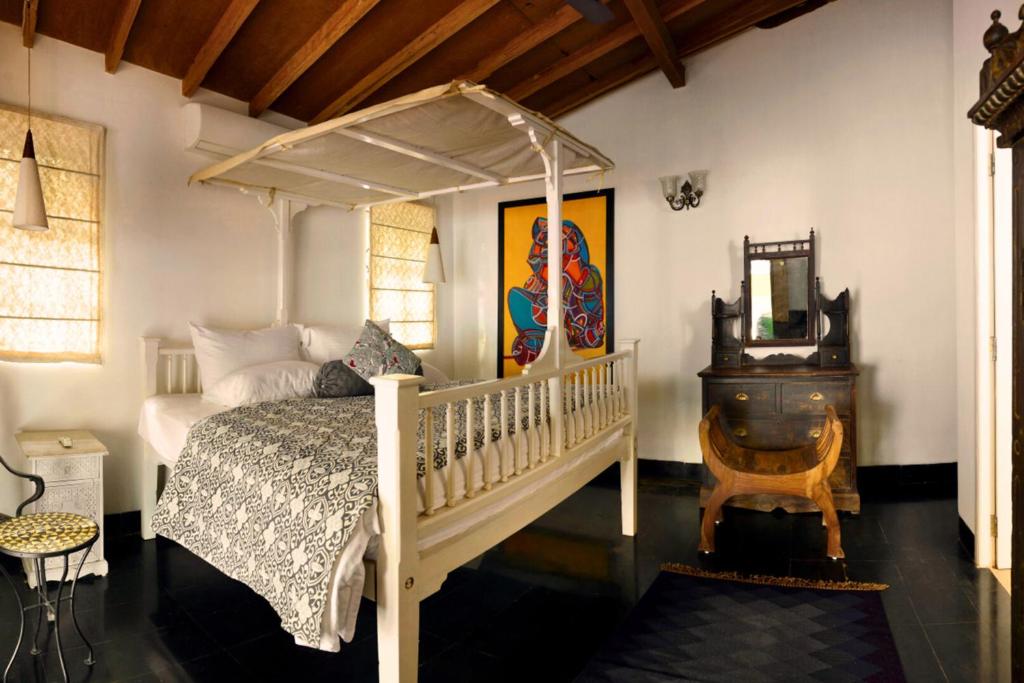 a bedroom with a canopy bed and a mirror at ELIVAAS Terra Rosa Portuguese-styled 4-BHK Villa With Private Pool, Garden, Veranda & Sit-out Area in Vainguinim