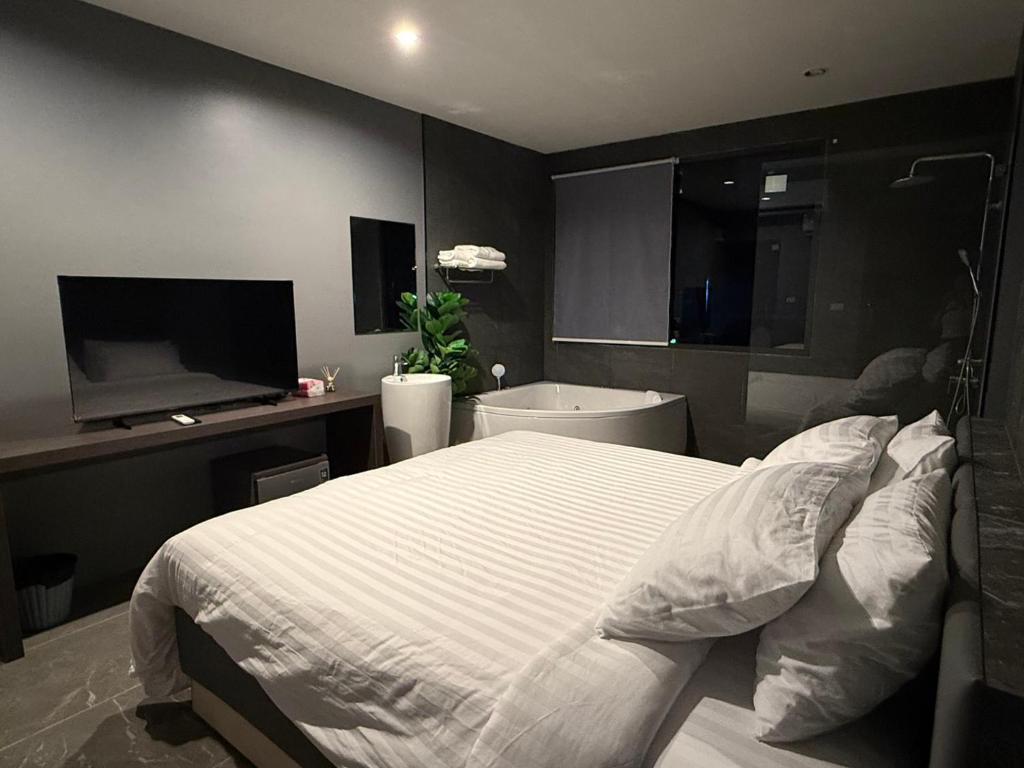 a bedroom with a bed and a tub and a television at HK Villa Resort in Bangkok