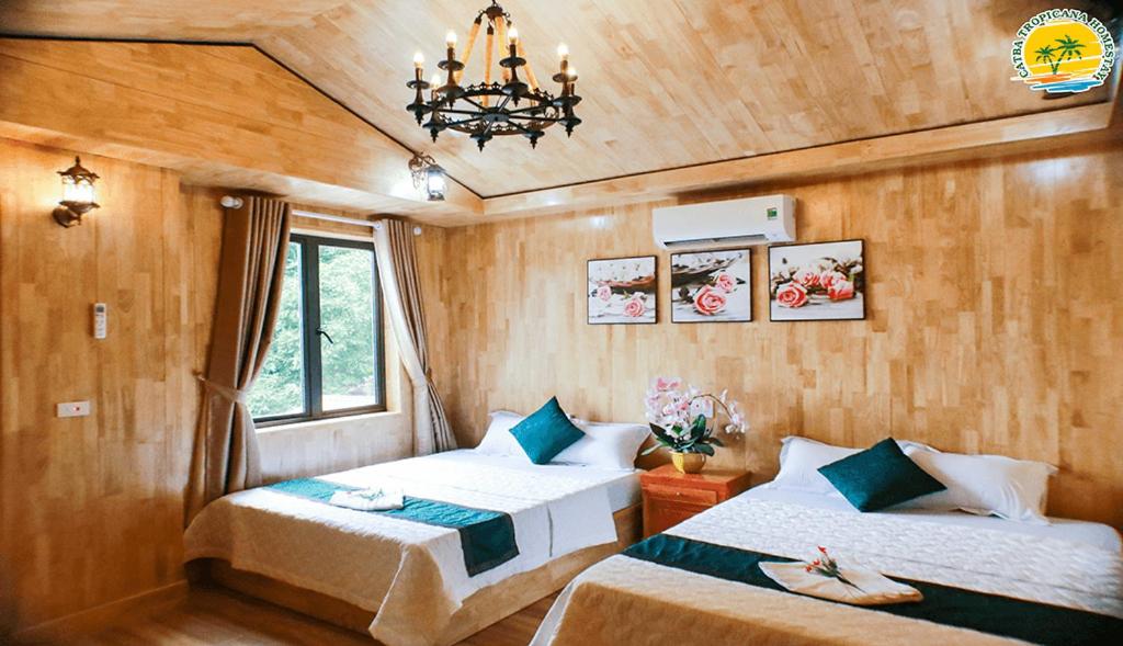 カットバ島にあるTROPICANA homestay 1のベッド2台とシャンデリアのある寝室