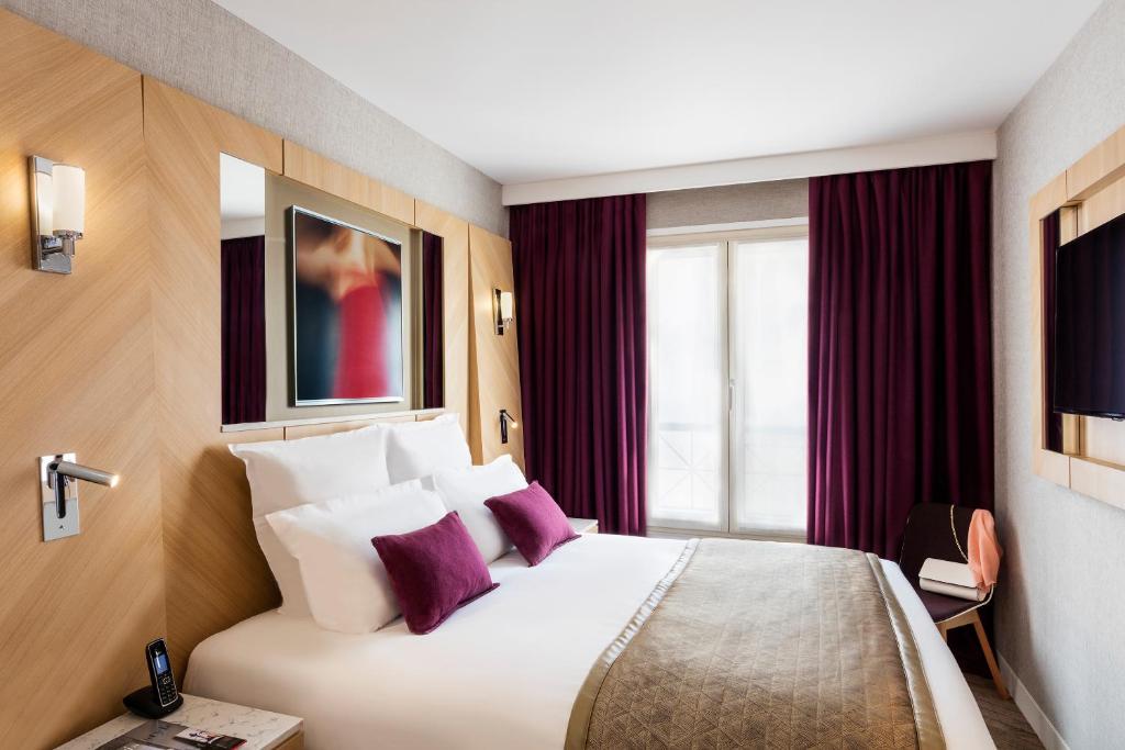a hotel room with a large white bed with purple pillows at Hotel Louvre Saint-Honoré in Paris