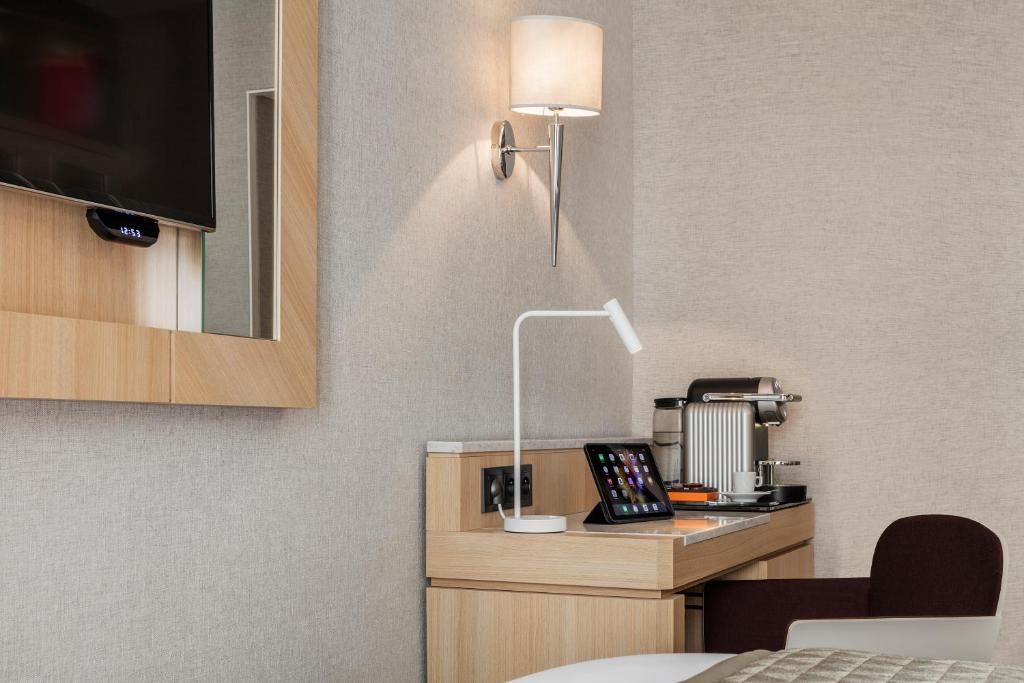 a hotel room with a desk with a lamp on it at Hotel Louvre Saint-Honoré in Paris