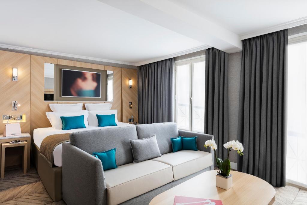 a hotel room with a bed and a couch at Hotel Louvre Saint-Honoré in Paris