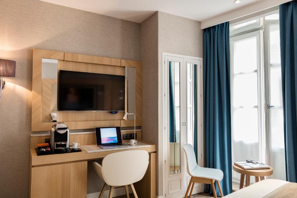 a hotel room with a desk with a computer in it at Hotel Louvre Saint-Honoré in Paris
