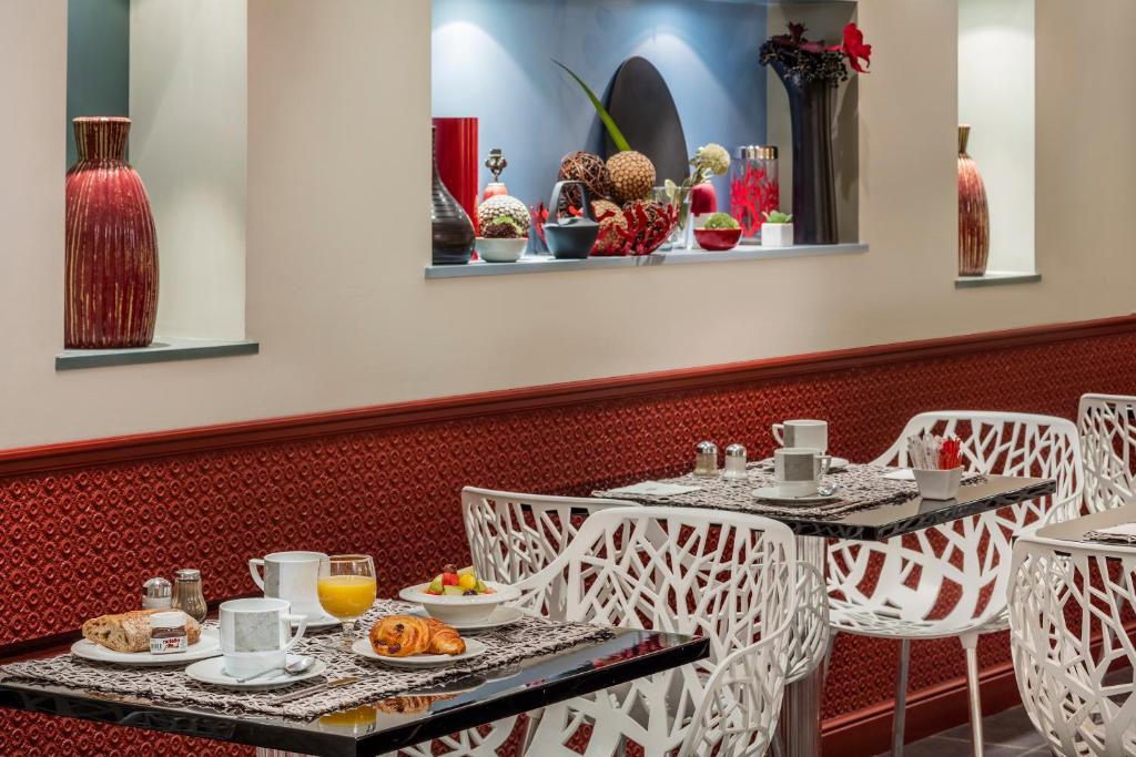 a dining room with two tables and chairs with food at Hotel Louvre Saint-Honoré in Paris