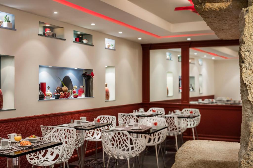 a dining room with tables and white chairs at Hotel Louvre Saint-Honoré in Paris