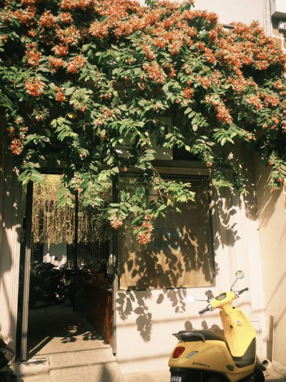 a scooter parked in front of a building with flowers at IKIGAI Dorm Hostel - Danang Beach in Danang