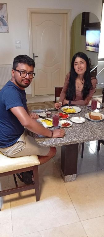 a man and a woman sitting at a table with food at Masa sharing home private rooms and private bathroom in Amman