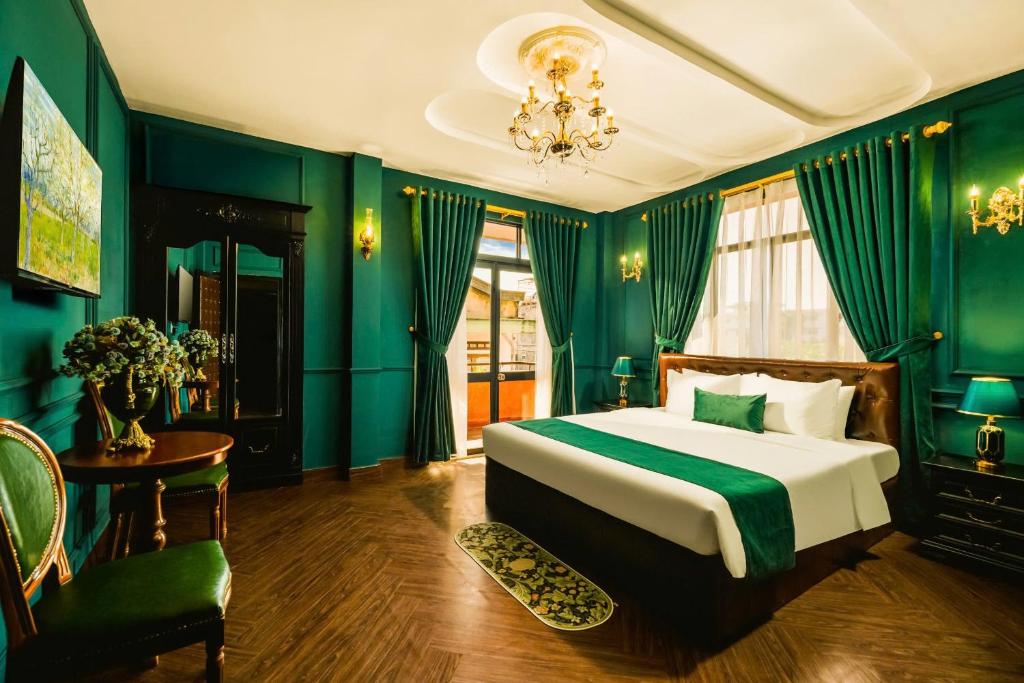 a bedroom with green walls and a bed and a chandelier at Vina Vintage Hotel in Hue