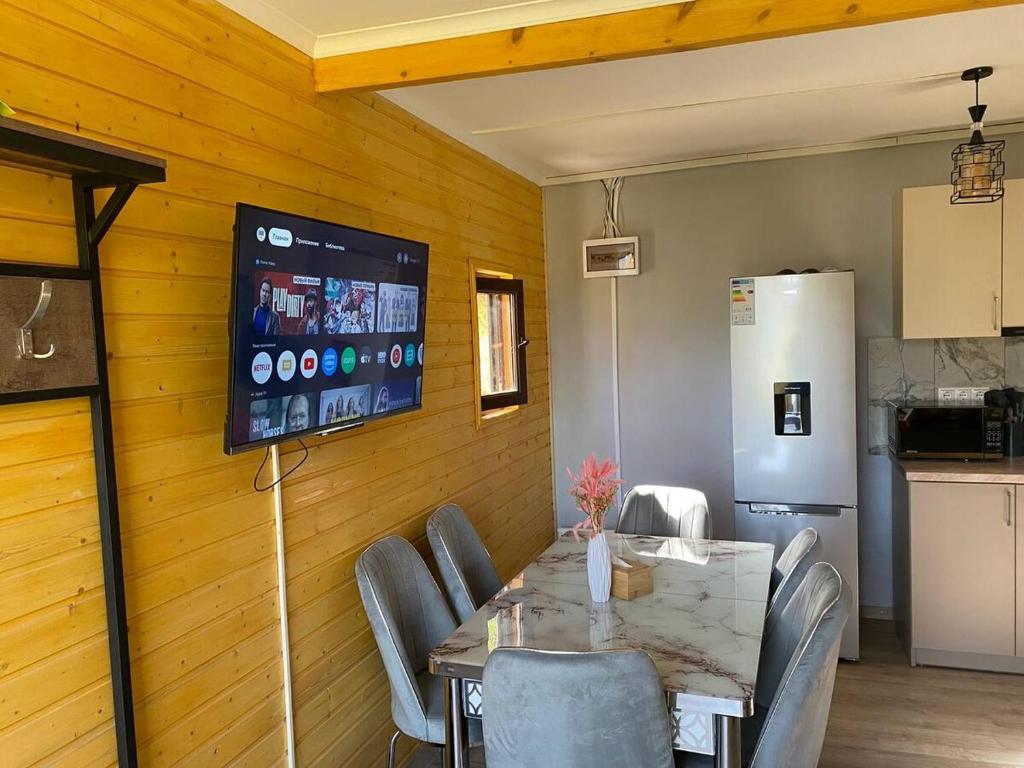 Un comedor con una mesa y un televisor en la pared. en Forest Panorama House Dilijan, en Dilijan