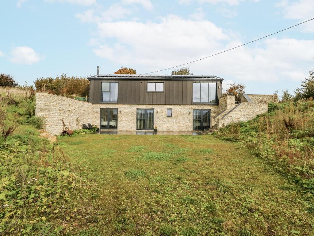 una casa de piedra con techo negro en una colina en Frogwell, en Sherborne
