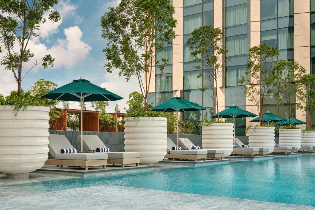 A landscaped outdoor pool is lined with shaded loungers.